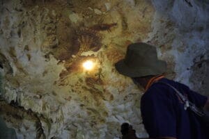 Seorang pemandu lokal menyorot cahaya senter ke lukisan tangan purba di dinding Gua Bloyot. Foto oleh Deta Widyananda.