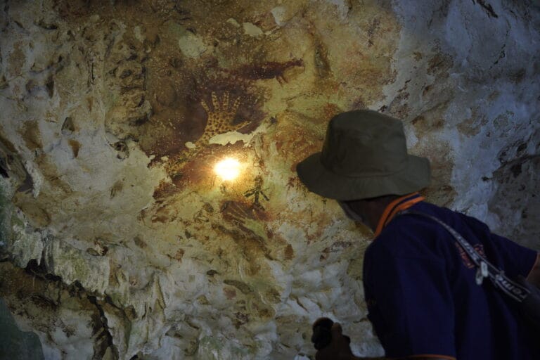 Seorang pemandu lokal menyorot cahaya senter ke lukisan tangan purba di dinding Gua Bloyot. Foto oleh Deta Widyananda.